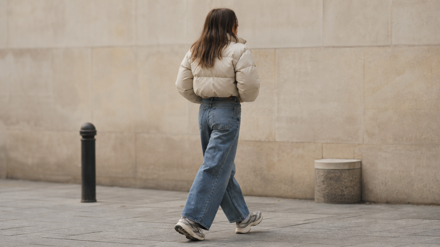 A woman in a cropped puffer jacket, turtleneck, and wide-leg jeans walking outside in winter.