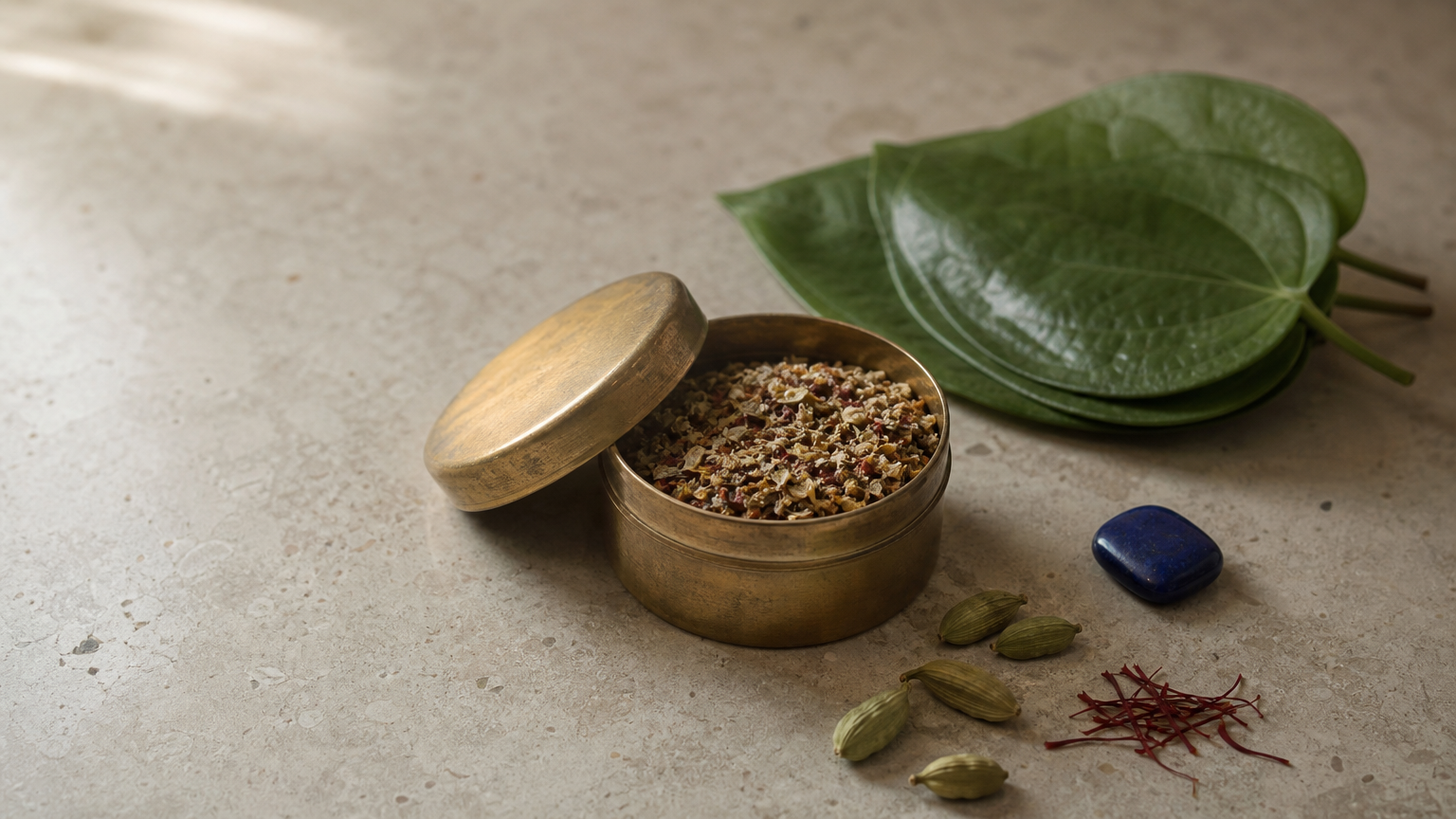 Open tin of herbal paan masala with betel leaves, cardamom pods, and saffron.