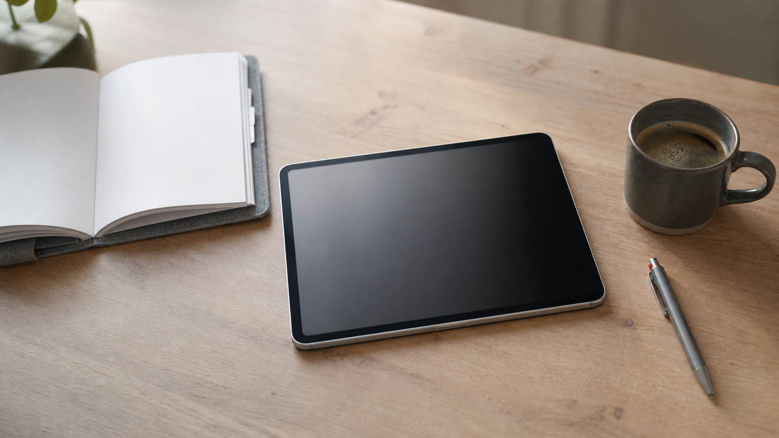 Ein Tablet liegt neben einer Einarbeitungsmappe und einem Kugelschreiber auf einem Schreibtisch.